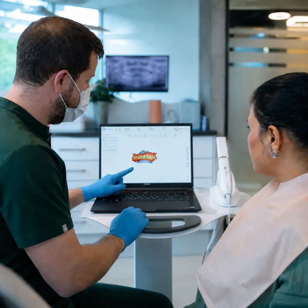 Dentist explaining digital dental design and precise fit planning to a patient using 3D dental technology in a modern clinic.